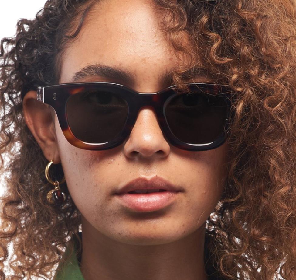 A close view of statement sunglasses styled with natural curls